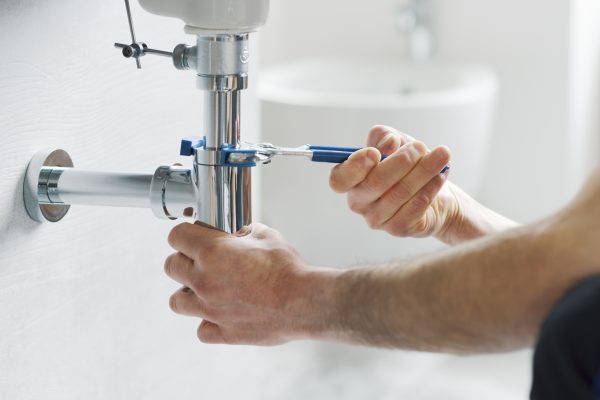 Professional plumber fixing a bathroom sink drain using water pump pliers
